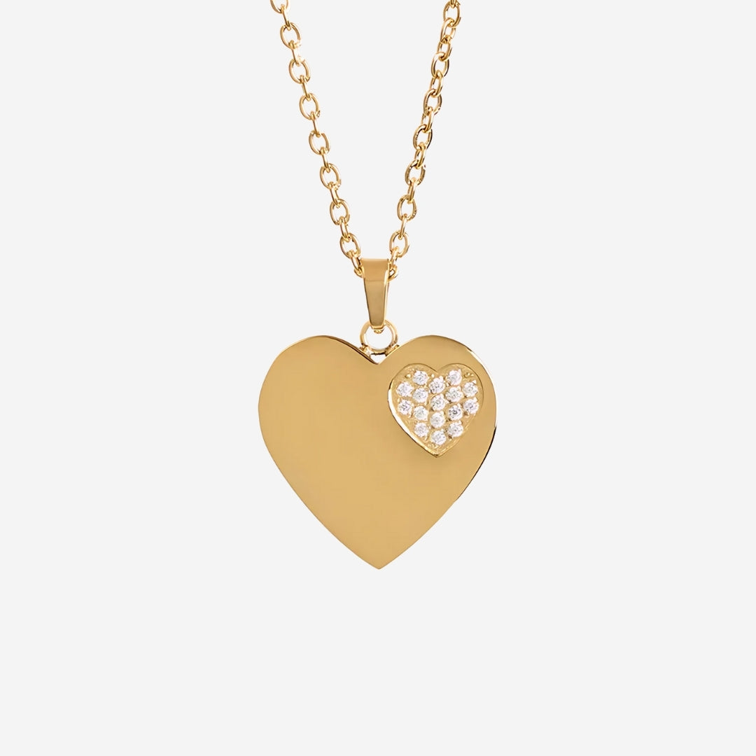 Gold heart-shaped necklace with a smaller heart inset on a light gray background