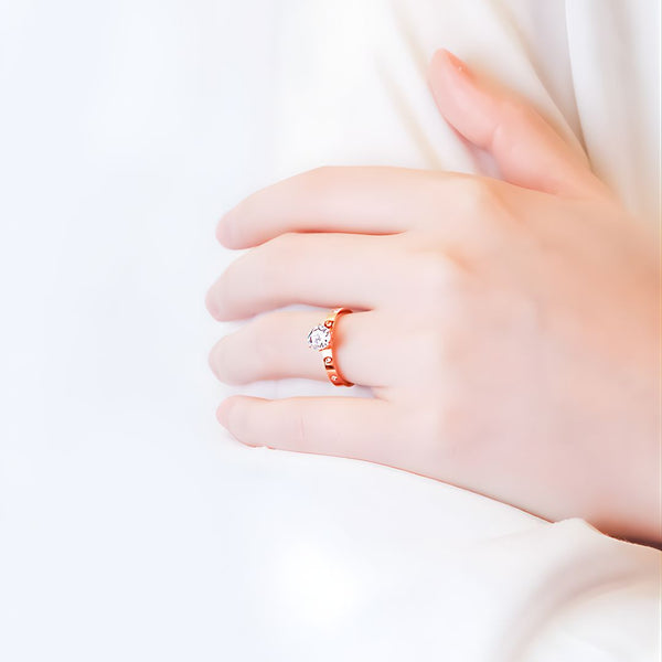 Hand wearing a rose gold ring with a diamond on a white background
