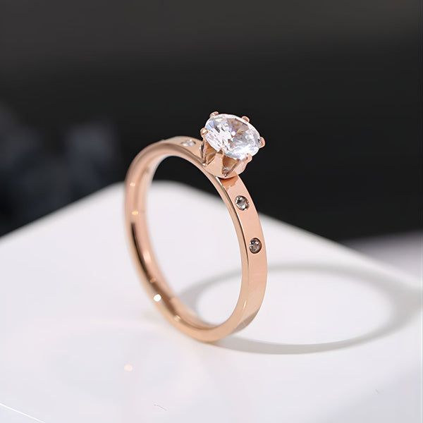 Rose gold ring with a diamond on a white surface
